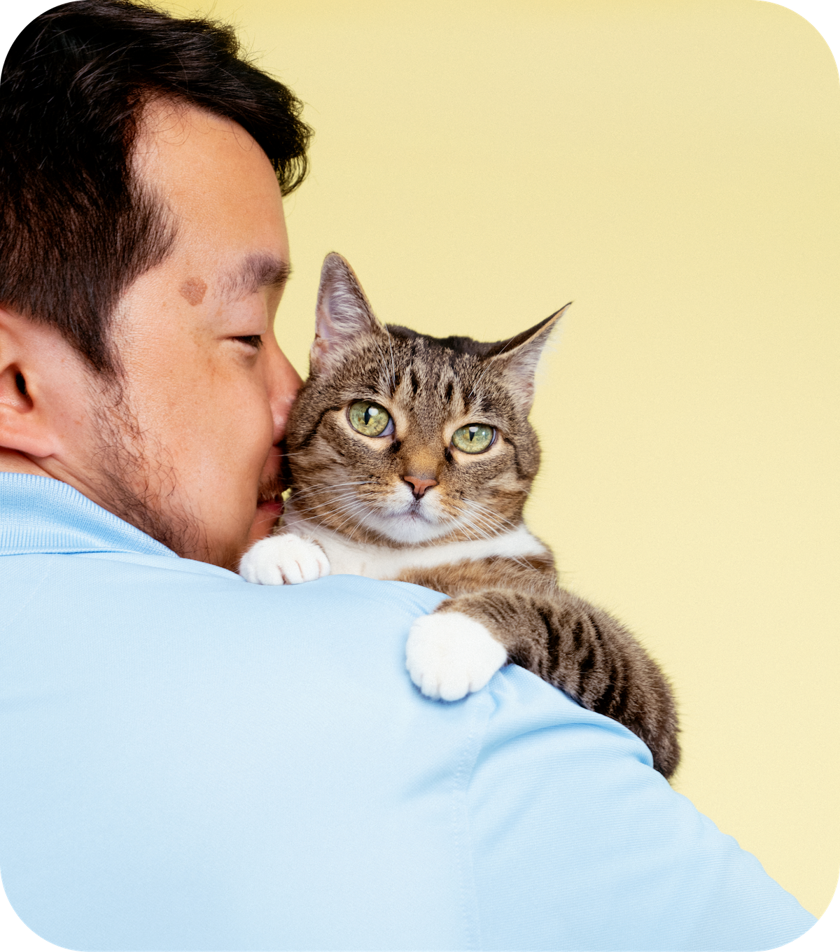 Man with glasses and blue shirt holding a dog close to him